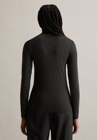 Langärmliges schwarzes Oberteil mit glatter Textur und figurbetonter Silhouette, mit minimalen Nähten und hohem Halsausschnitt, von hinten gezeigt.