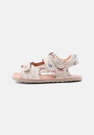Sandale blanche pour tout-petit avec motif de dinosaure, deux brides réglables en Velcro, orteil et talon ouverts, et semelle plate en caoutchouc.