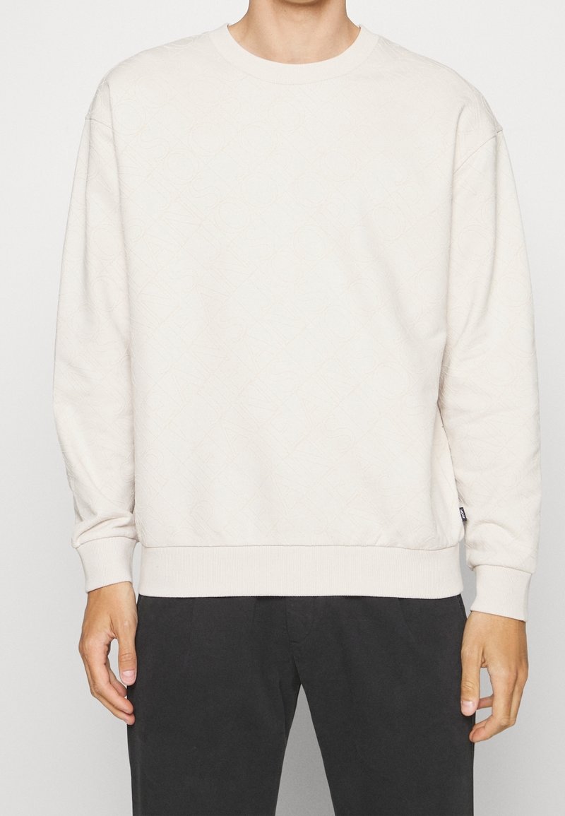 Felpa beige chiaro con un motivo testurizzato, scollatura rotonda e polsini e orlo a coste. Realizzata in una morbida miscela di tessuti per il massimo comfort.