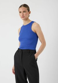 Blauw geribbelde tanktop met een hoge halslijn en brede armsgaten, gecombineerd met zwarte op maat gemaakte broeken met zakken en een zachte textuur.