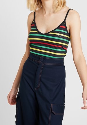 Gestreept tanktop met zwart, groen, geel en rood. Voorzien van dunne bandjes, een V-hals en een geborduurd logo. Gecombineerd met donkere broek.