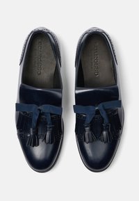 Zapatos de cuero azul marino con un acabado suave, que cuentan con un flequillo decorativo y borlas, además de un upper texturizado para añadir detalle.