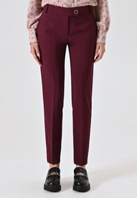Bordeaux op maat gemaakte broek met een flat front, slim fit en een riemlus met een ronde accenten. Gemaakt van gladde stof. Gecombineerd met zwarte instapschoenen.