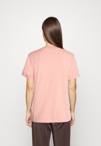 T-shirt à manches courtes et col rond en coton doux rose, avec une coupe décontractée et un dos uni sans embellissements.