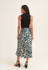 Black sleeveless top paired with a teal and cream zebra print skirt, featuring a flowy design and block-heeled sandals.