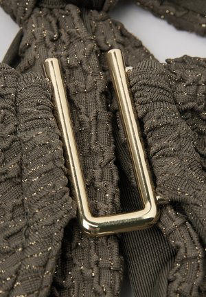 Hebilla rectangular dorada sobre tela texturizada gris oscuro con hilo metálico, mostrando detalles de punto fruncido y acanalado.