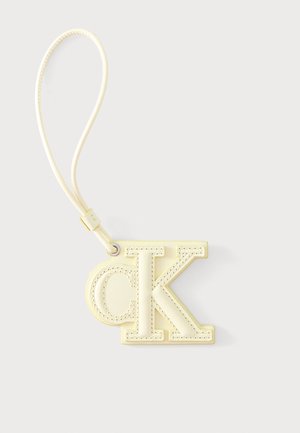 Nøglekæde i cremet læder med syede initialer "ck" og en løkke stroppen fastgjort med en sølv metal-ring.