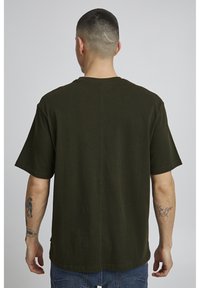 Olivegrøn, løstsiddende T-shirt lavet af tekstureret bomuld, med korte ærmer og rund hals, med en midtersøm ned ad ryggen.
