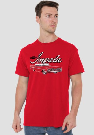 Red cotton T-shirt with a graphic print of a vintage Chevrolet Impala. The design features black and white accents and bold lettering.