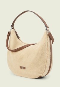 Torebka w kolorze kremowym, z miękką fakturą, o zaokrąglonej sylwetce, z brązowym skórzanym paskiem i srebrnymi akcentami na froncie.
