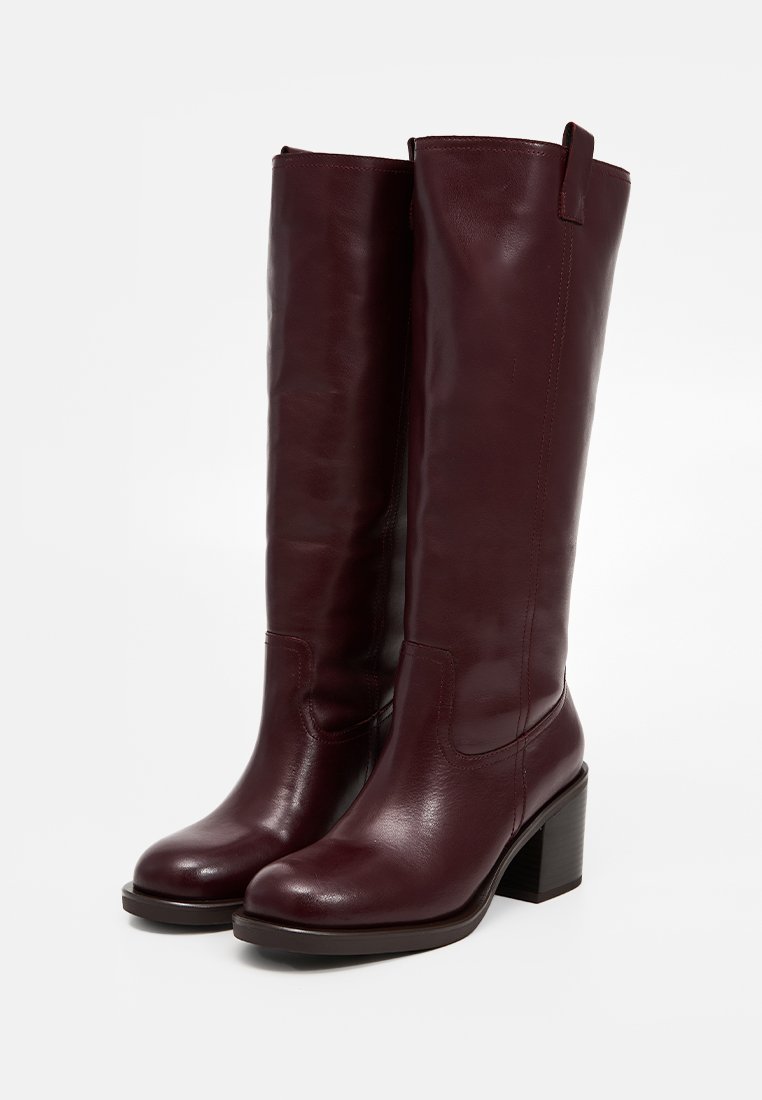 Botas de cuero burdeos hasta la rodilla con una textura suave, tacón cuadrado y una cinta en la parte superior para facilitar su colocación.