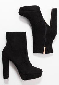 Czarne ankle bootsy na wysokim obcasie wykonane z zamszu, z platformą, zwężonym kształtem oraz bocznym zamkiem błyskawicznym z złotym akcentem.
