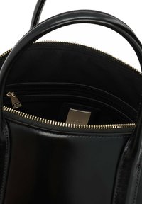 Melnas ādas rokassoma ar zelta krāsas rāvējslēdzēju. Interjerā ir auduma oderējums, rāvējslēdzēja kabata un zīmola etiķete. Divas izturīgas rokturi.