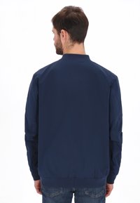 Marineblå bomberjakke med ribbet krave, elastiske ærmekanter og talje. Fremstillet af glat stof med et enkelt design uden mønstre.