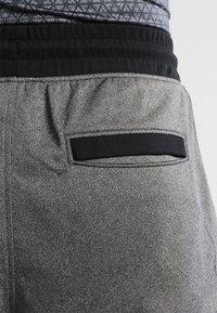 Grå idretts shortser med en teksturert overflate, med et svart elastisk liv og en mindre svart lomme bak.
