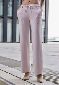 Svetloružové nohavice s širokými nohavicami vyrobené z mäkkej tkaniny, so bočnými vreckami, sťahovacím pásom a čistou, hladkou textúrou.
