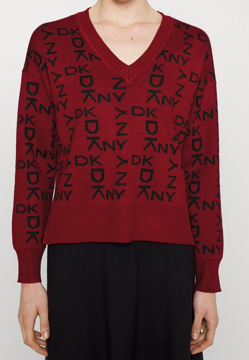 Roter Stricksweater mit V-Ausschnitt, langen Ärmeln und einem allover DKNY-Logo-Muster in Schwarz. Glatte Textur mit lässiger Passform.
