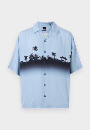 Jasnoniebieska koszula na krótki rękaw z guzikami, z czarnym wzorem sylwetek palm i chat na wysokości klatki piersiowej i górnej części tułowia.