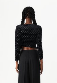Μαύρη βελούδινη μπλούζα μακρυμάνικη με διαμαντένιο μοτίβο από ασημί λεπτομέρειες. Διαθέτει cropped σχέδιο με ρυτιδωμένα μανίκια. Απαλή υφή.