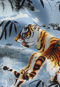 Mönstrad tyg med en livfull orange och svart tiger mot en blå bakgrund med ljusa moln och bambublad. Slät textur.