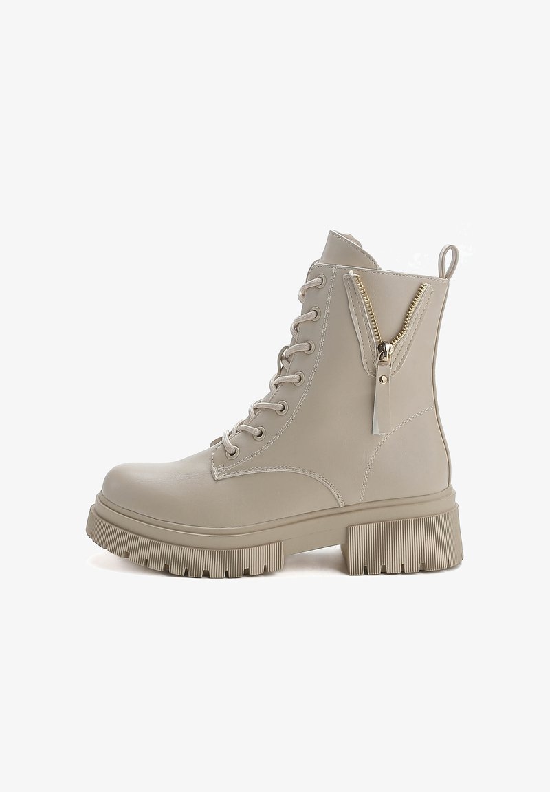 Botas de tobillo beige con material sintético suave, suela de goma plana y detalle de cremallera lateral con herrajes dorados. Diseño con cordones en la parte delantera.