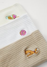 Tres bandas de tela acanalada apiladas horizontalmente en crema, blanco y beige. Cada una presenta coloridos diseños bordados: una bebida, una dona y un perro.