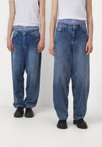 Světle modré volné džínové kalhoty s vysokým pasem, s proužkovanou vnitřní podšívkou, předními kapsami a zapínáním na knoflík.