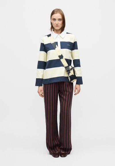 Striped long-sleeve shirt in yellow and navy with a white collar; paired with wide-leg red and navy striped pants; adjustable crossbody bag.