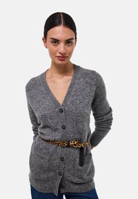 Cardigan gris avec un col en V, fermeture à boutons et poignets côtelés, associé à une ceinture à imprimé léopard. Texture douce, coupe décontractée et poches.