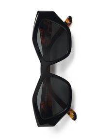Lunettes de soleil noires surdimensionnées avec une monture angulaire, des verres sombres et des accents en écaille de tortue sur les branches. Matériau plastique lisse.