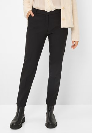 Pantaloni neri sartoriali con taglio slim, dotati di chiusura con un bottone, tasche laterali e tessuto morbido. Abbinati a stivaletti neri.