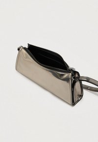 Ασημί μεταλλική τσάντα χειρός με γυαλιστερή επιφάνεια, κλείσιμο με φερμουάρ και αποσπώμενο λουράκι καρπού. Το εσωτερικό αποκαλύπτει μαύρη επένδυση.