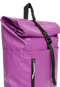 Paarse roll-top rugzak gemaakt van duurzaam, waterproof materiaal. Beschikt over een voorzak met rits, zwarte accenten en een handvat aan de bovenkant voor het dragen.