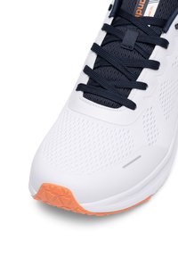 Bela športna čevlja z zračnim mrežnim zgornjim delom, mornarskimi vezalkami in teksturiranim oranžnim podplatom. Ima dovršen dizajn in podporno strukturo.