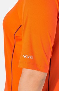 Oranžové sportovní tričko s krátkým rukávem, které má texturovanou látku, fialové akcenty na šití a bílé logo "sport" na rukávu.