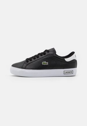 Sort lavtop Lacoste sneaker med hvid sål og hælfane, tekstureret læder, sorte snørebånd og grønt krokodillelogo på siden.