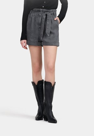 Shorts en denim gris avec taille ceinturée, ourlets retroussés et poches avant, associés à des bottes en cuir noir montant jusqu'au genou avec un bout pointu.