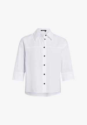 Weißes Hemd mit spitzem Kragen, Dreiviertelärmeln, schwarzen Knöpfen auf der Vorderseite und geradem Saum. Glatte Textur des Stoffes.