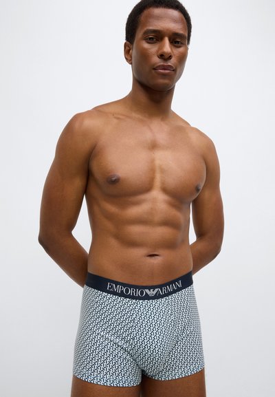 Μπόξερ σε μπλε και άσπρο γεωμετρικό μοτίβο, με μπλε σκούρο ζωνάρι με επωνυμία. Κατασκευασμένα από απαλό ύφασμα, σχεδιασμένα για άνεση.