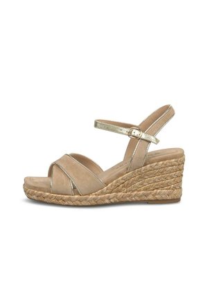 Beige sleehaksandaal met gevlochten jutezool, gekruiste voorste banden en een gouden enkelriem met gespsluiting.