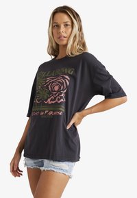 Sort oversized t-shirt med grafisk tryk, der viser palmeblade og en abstrakt rose. Blødt bomuldsstof, korte ærmer og afslappet pasform.