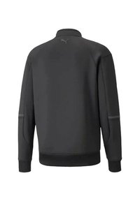 Chaqueta deportiva negra con un cuello alto, puños elásticos y un acabado texturizado. Sutil detalle del logotipo en la parte posterior.