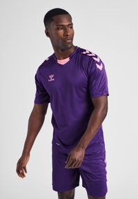 Purple athletic jersey with short sleeves, pink shoulder accents, and a v-neck design, paired with matching shorts. Lightweight fabric.