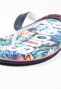 Infradito con un motivo floreale multicolore sulla soletta, cinturini blu navy e scritte bianche. Suola piatta in gomma con dettagli testurizzati.