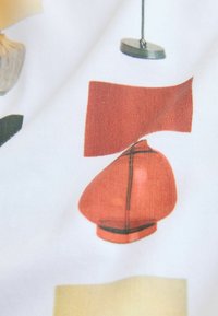 Material textil cu fundal alb decorat cu forme colorate imprimate, inclusiv lămpi roșii și portocalii și diverse modele geometrice.