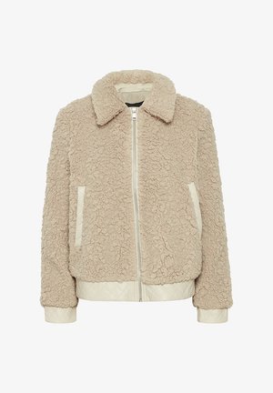 Veste en polaire beige avec une surface texturée, un col, une fermeture éclair à l'avant et des accents en crème matelassés sur les poches et l'ourlet.