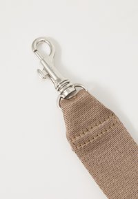 Cintura in tessuto beige con un robusto gancio in metallo. Presenta cuciture visibili e una superficie testurizzata. Adatta per vari attacchi.