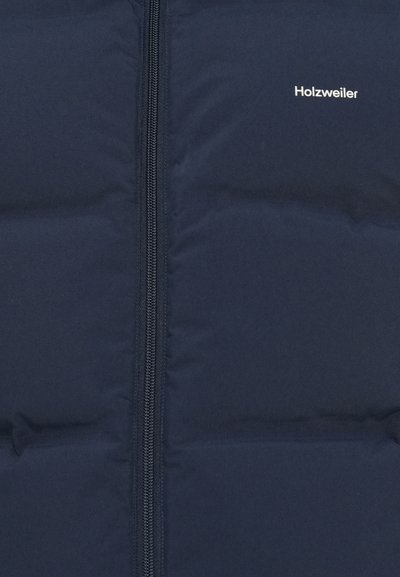 Jachetă puffer bleu marin cu un design matlasat. Dispune de un fermoar central și numele brandului "Holzweiler" în alb în partea stângă sus.