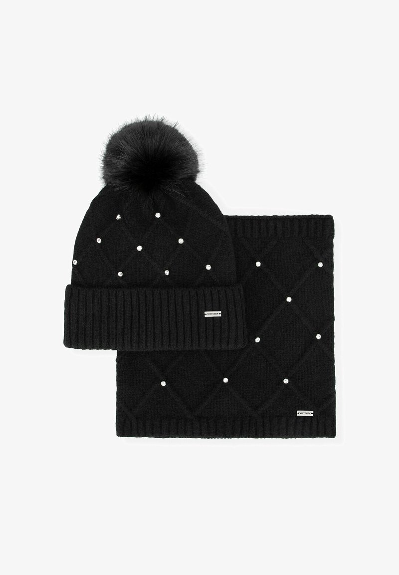 Cuffia nera lavorata a maglia con pon pon in pelliccia e motivo a diamante, decorata con piccoli perline bianche, abbinata a una sciarpa nera coordinata.