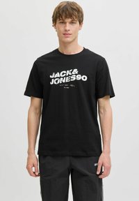 Sort bomulds T-shirt med hvid grafiktryk "JACK & JONES" på forsiden. Rund hals og korte ærmer, afslappet pasform.